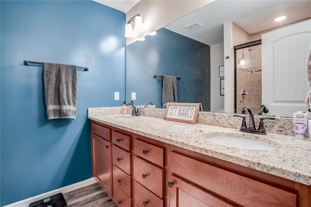 1609 Bluestem Dr, Ottawa, KS 66067 - bathroom with double vanity, baseboards, tiled shower, and wood finished floors