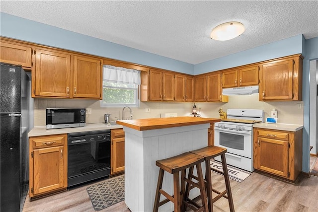 1805 N Lazy Branch Rd, Independence, MO 64058 - kitchen featuring black appliances, under cabinet range hood, a sink, light wood-style flooring, and a textured ceiling