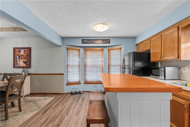 1805 N Lazy Branch Rd, Independence, MO 64058 - kitchen with freestanding refrigerator, light wood-style floors, a textured ceiling, butcher block counters, and brown cabinets