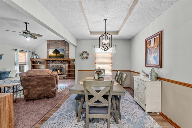 1805 N Lazy Branch Rd, Independence, MO 64058 - dining space with a textured ceiling, ceiling fan, light wood-style flooring, a brick fireplace, and a chandelier