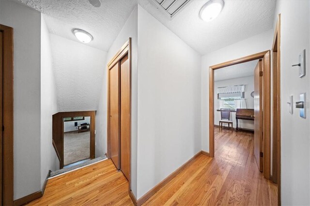 1107 E 110th St, Kansas City, MO 64131 - hallway with light wood finished floors, a textured ceiling, and baseboards