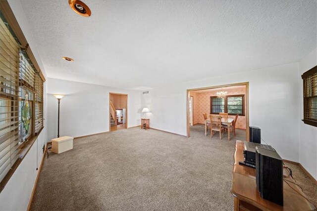 1107 E 110th St, Kansas City, MO 64131 - carpeted living area with a textured ceiling and a chandelier