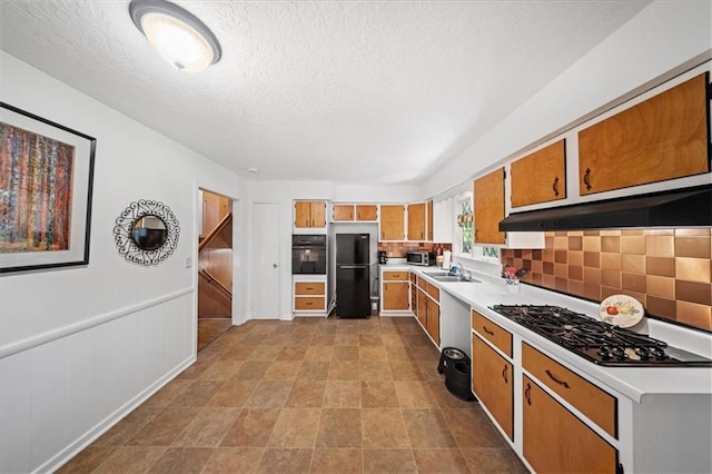 1107 E 110th St, Kansas City, MO 64131 - kitchen featuring black appliances, light countertops, brown cabinetry, exhaust hood, and tasteful backsplash