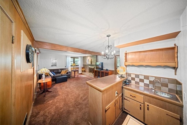 1107 E 110th St, Kansas City, MO 64131 - kitchen with a sink, carpet, a peninsula, a chandelier, and a textured ceiling