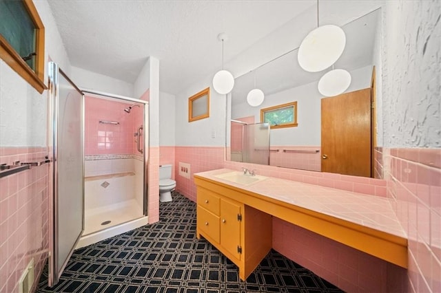 1107 E 110th St, Kansas City, MO 64131 - bathroom with tile walls, toilet, a wainscoted wall, a stall shower, and vanity