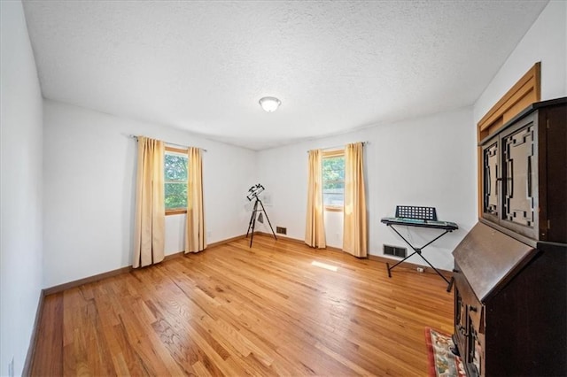 1107 E 110th St, Kansas City, MO 64131 - workout area with light wood-style flooring, baseboards, and a textured ceiling