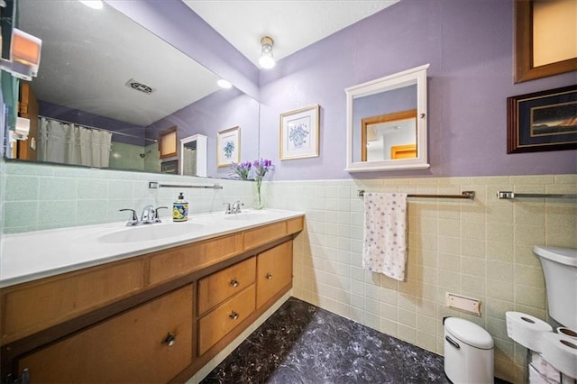 1107 E 110th St, Kansas City, MO 64131 - full bathroom featuring tile walls, double vanity, toilet, curtained shower, and a wainscoted wall