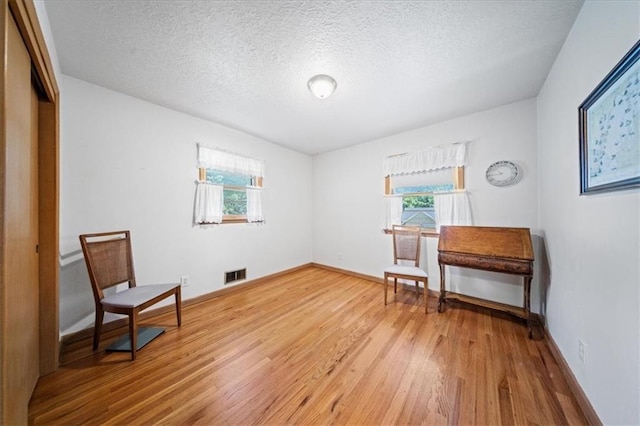 1107 E 110th St, Kansas City, MO 64131 - living area featuring plenty of natural light, light wood-style floors, a textured ceiling, and baseboards