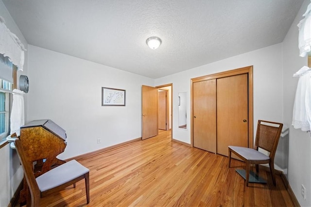 1107 E 110th St, Kansas City, MO 64131 - sitting room with light wood-style floors, baseboards, and a textured ceiling