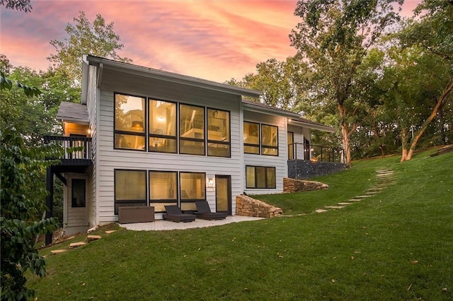 12204 Catalina St, Leawood, KS 66209 - back of property at dusk with a lawn, a balcony, and a patio