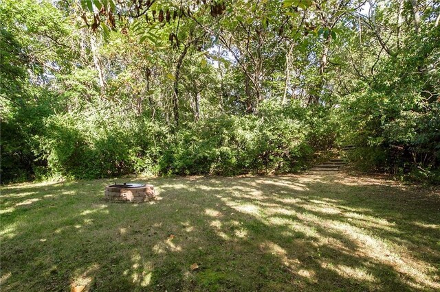12204 Catalina St, Leawood, KS 66209 - view of grassy yard featuring an outdoor fire pit and a forest view