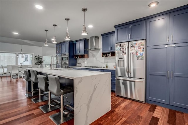 12204 Catalina St, Leawood, KS 66209 - kitchen with stainless steel appliances, wall chimney exhaust hood, blue cabinetry, a breakfast bar area, and recessed lighting