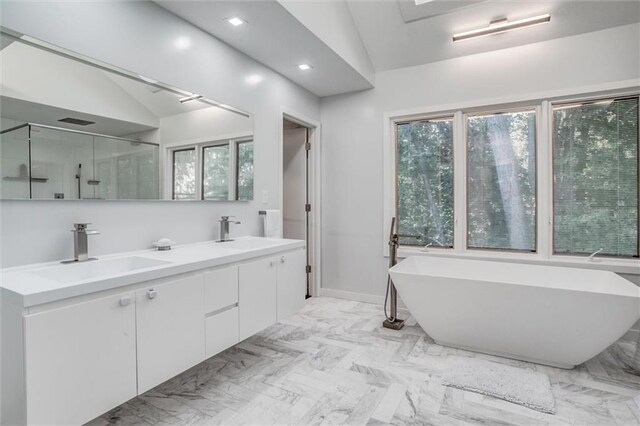 12204 Catalina St, Leawood, KS 66209 - bathroom with vaulted ceiling, plenty of natural light, a soaking tub, double vanity, and a shower with door