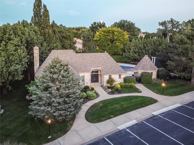 12204 Catalina St, Leawood, KS 66209 - view of front of property with uncovered parking, a front lawn, stone siding, and a chimney