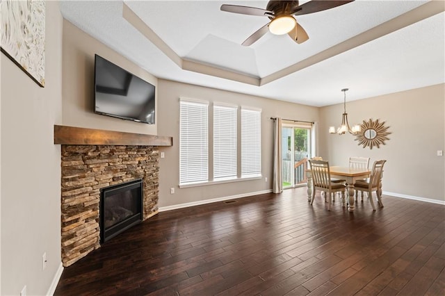 20740 W 224th St, Spring Hill, KS 66083 - living room with ceiling fan, a stone fireplace, a raised ceiling, a chandelier, and dark wood-style floors