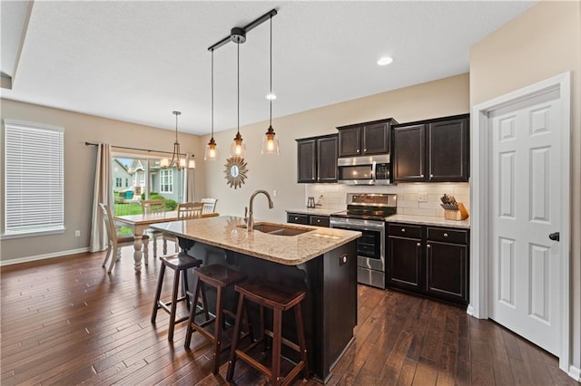 20740 W 224th St, Spring Hill, KS 66083 - kitchen featuring appliances with stainless steel finishes, backsplash, a kitchen breakfast bar, dark wood-style flooring, and an island with sink