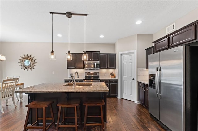 20740 W 224th St, Spring Hill, KS 66083 - kitchen with stainless steel appliances, dark wood-style floors, tasteful backsplash, a breakfast bar area, and light stone countertops