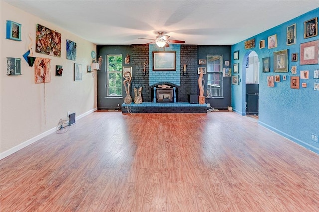 19490 Countryside Cir, Weston, MO 64098 - unfurnished living room featuring wood finished floors, a fireplace, a ceiling fan, baseboards, and arched walkways