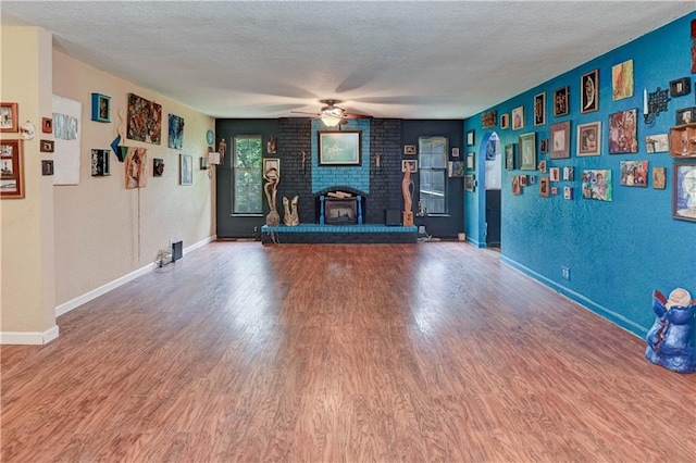 19490 Countryside Cir, Weston, MO 64098 - unfurnished living room featuring wood finished floors, a ceiling fan, a brick fireplace, baseboards, and a textured ceiling