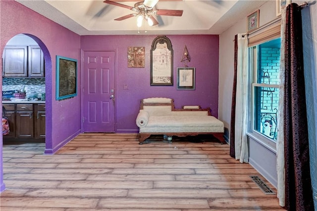 19490 Countryside Cir, Weston, MO 64098 - bedroom featuring light wood finished floors, a raised ceiling, a textured wall, arched walkways, and a ceiling fan