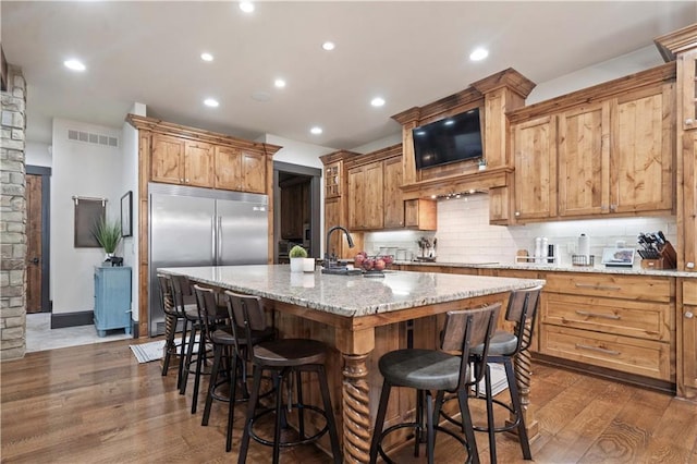 11106 W 146th Ter, Overland Park, KS 66221 - kitchen with built in refrigerator, a sink, wood finished floors, backsplash, and a kitchen breakfast bar