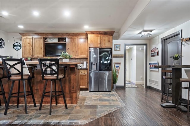 11106 W 146th Ter, Overland Park, KS 66221 - kitchen featuring stainless steel fridge, a breakfast bar area, baseboards, brown cabinets, and recessed lighting