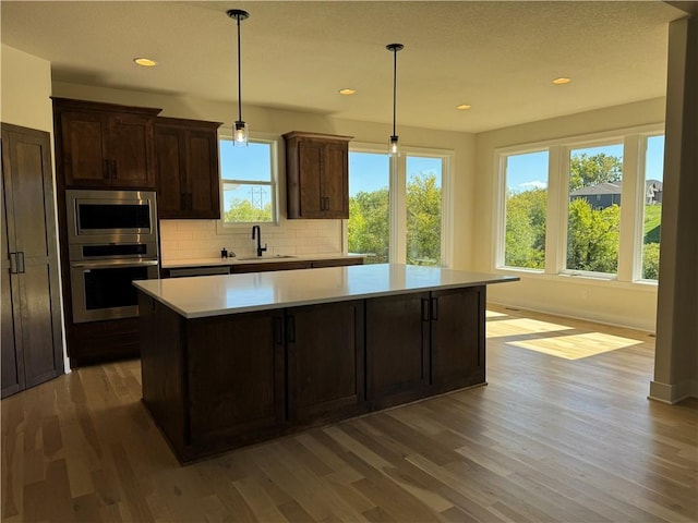 22415 87th Ter, Lenexa, KS 66227 - kitchen with appliances with stainless steel finishes, a sink, wood finished floors, a kitchen island, and light countertops