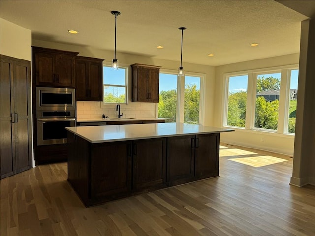 22415 87th Ter, Lenexa, KS 66227 - kitchen with stainless steel appliances, a center island, decorative backsplash, wood finished floors, and recessed lighting