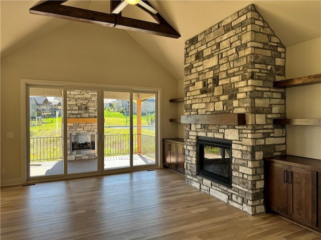 22415 87th Ter, Lenexa, KS 66227 - unfurnished living room with a stone fireplace, wood finished floors, beam ceiling, ceiling fan, and high vaulted ceiling
