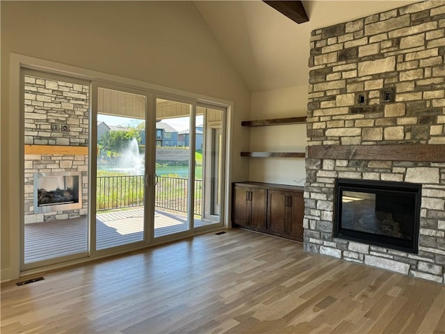22415 87th Ter, Lenexa, KS 66227 - unfurnished living room featuring a stone fireplace, lofted ceiling, and light wood finished floors
