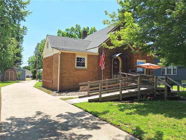 811 W Main St, Chanute, KS 66720 - view of front facade featuring brick siding, a front lawn, a chimney, and roof with shingles