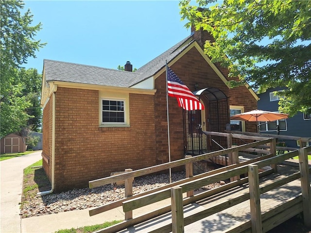 811 W Main St, Chanute, KS 66720 - view of side of property with a chimney, brick siding, and a shingled roof