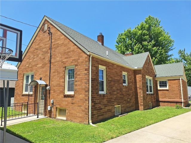 811 W Main St, Chanute, KS 66720 - view of side of home with a chimney, a lawn, a shingled roof, and brick siding