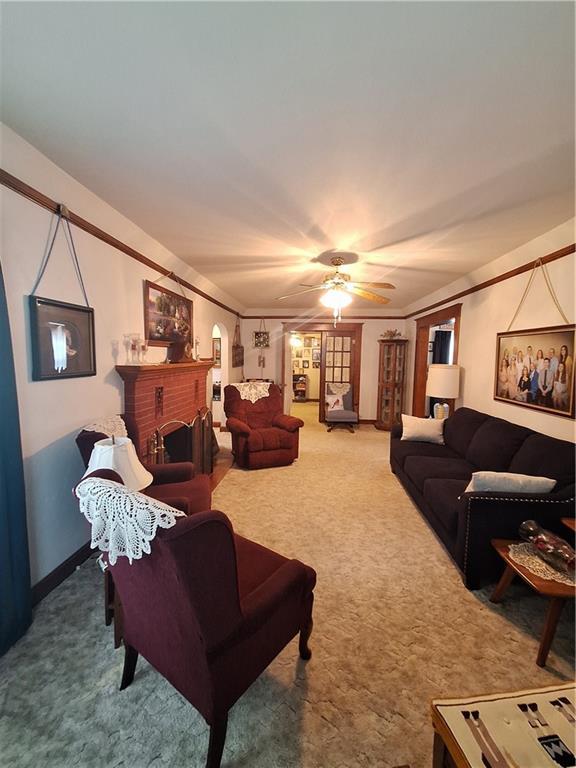 811 W Main St, Chanute, KS 66720 - living area with carpet floors, ceiling fan, and a fireplace