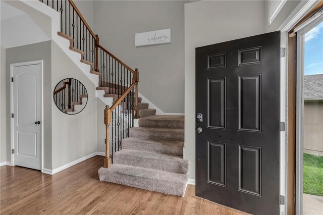 9915 Webster Cir, Kansas City, KS 66109 - entryway with wood finished floors, plenty of natural light, stairs, baseboards, and a high ceiling