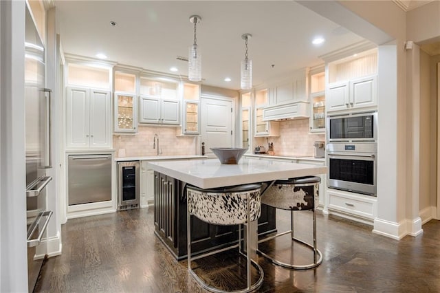 4801 W 133rd St Unit 103, Leawood, KS 66209 - kitchen with stainless steel appliances, wine cooler, a kitchen island, light countertops, and dark wood-style flooring