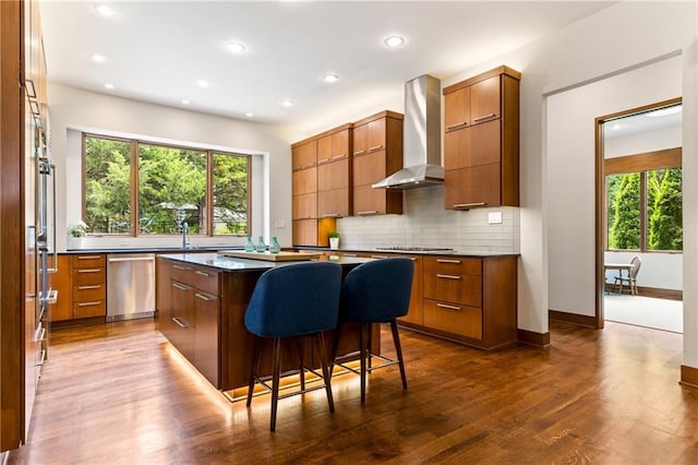 25075 W 105th Ter, Olathe, KS 66061 - kitchen with wall chimney range hood, stainless steel appliances, modern cabinets, brown cabinets, and recessed lighting