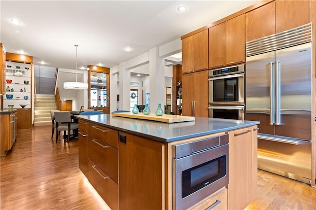 25075 W 105th Ter, Olathe, KS 66061 - kitchen with built in appliances, dark countertops, a center island, light wood-type flooring, and recessed lighting