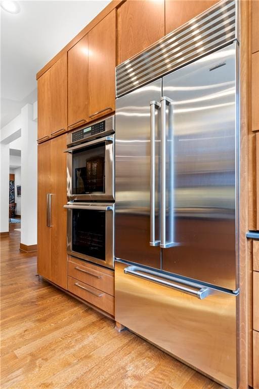 25075 W 105th Ter, Olathe, KS 66061 - kitchen with stainless steel appliances, light wood-style flooring, and brown cabinetry