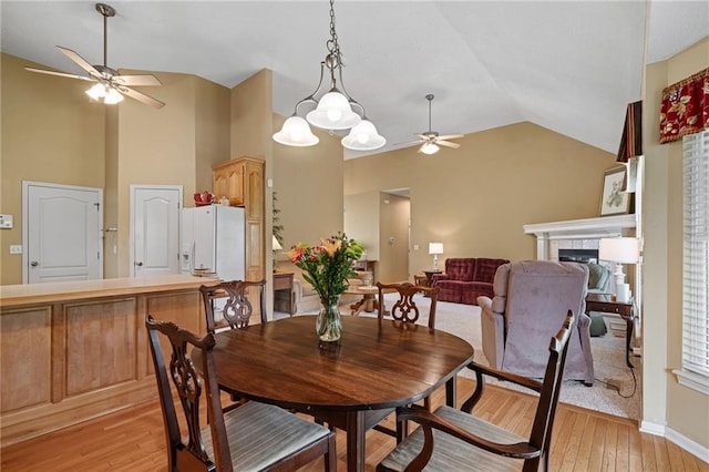 14175 W 155th St, Olathe, KS 66062 - dining room with ceiling fan, vaulted ceiling, a tile fireplace, light wood-style floors, and baseboards