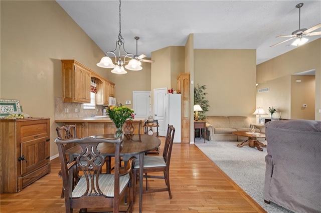 14175 W 155th St, Olathe, KS 66062 - dining room featuring high vaulted ceiling, light wood-style flooring, a ceiling fan, and a chandelier