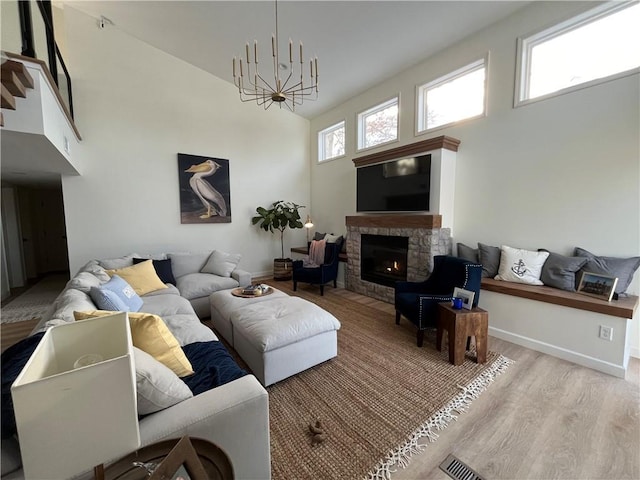 53 Z St, Lees Summit, MO 64086 - living room featuring a towering ceiling, a stone fireplace, light wood finished floors, baseboards, and a chandelier