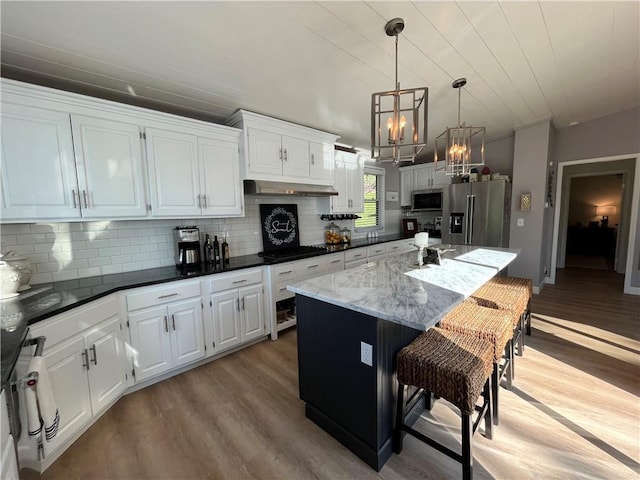53 Z St, Lees Summit, MO 64086 - kitchen featuring appliances with stainless steel finishes, a chandelier, light wood-style flooring, decorative backsplash, and a kitchen bar