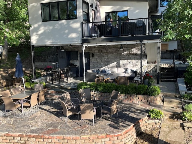 53 Z St, Lees Summit, MO 64086 - rear view of house featuring a balcony, outdoor dining area, an outdoor living space with a fire pit, a patio area, and stucco siding