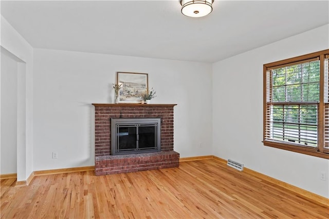 4417 E 104th St, Kansas City, MO 64137 - unfurnished living room featuring wood finished floors, baseboards, and a brick fireplace