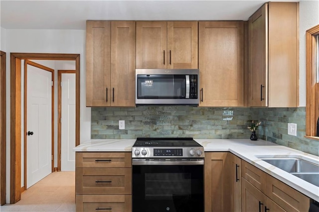 4417 E 104th St, Kansas City, MO 64137 - kitchen featuring appliances with stainless steel finishes, decorative backsplash, light countertops, and brown cabinets
