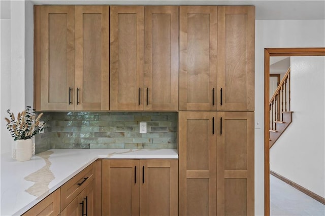 4417 E 104th St, Kansas City, MO 64137 - kitchen featuring backsplash, brown cabinetry, and baseboards