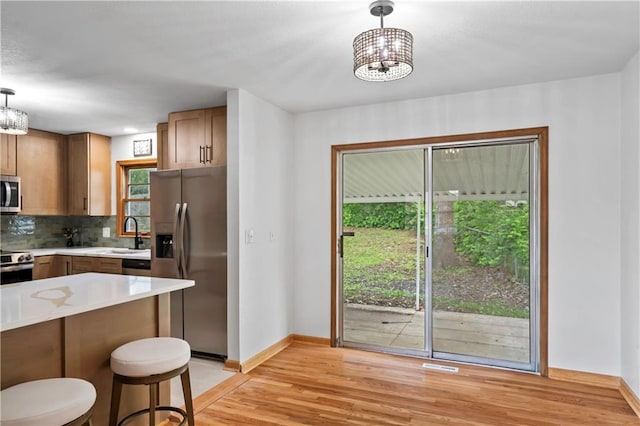 4417 E 104th St, Kansas City, MO 64137 - kitchen with appliances with stainless steel finishes, a chandelier, light wood-style floors, and a sink