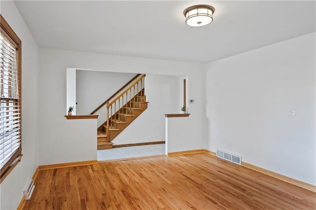 4417 E 104th St, Kansas City, MO 64137 - empty room featuring wood finished floors, baseboards, and stairway