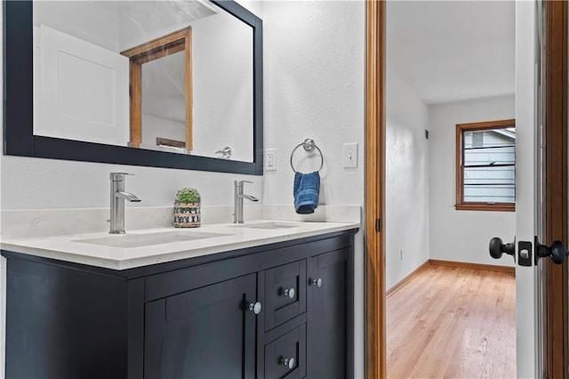 4417 E 104th St, Kansas City, MO 64137 - bathroom featuring double vanity, wood finished floors, and baseboards